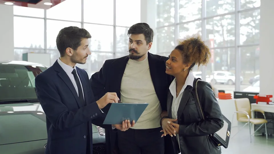 Customers talking with a vehicle sales advisor in a dealership